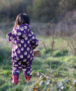 Child wearing the Little Green Radicals purple sleeping swans print sherpa lined snowsuit with red wellington boots. View of back of suit showing hood down.