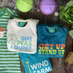 A flatlay featuring the four Little Green Radicals slogan playsuits. Three are folded up with one just off to the side laid out flat 