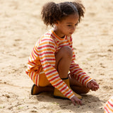 Child wearing the Little Green Radicals sorbet striped UPF 50 sunsafe long sleeve rash vest with yellow swim shorts. 