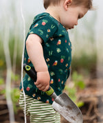 Child wearing the Little Green Radicals Spring garden organic cotton playset outfit. Repeat pattern green t-shirt and green and cream striped joggers. 