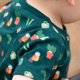Close up of the repeat garden illustration themed print on the t-shirt from the Little Green Radicals Spring garden organic cotton playset being worn. 