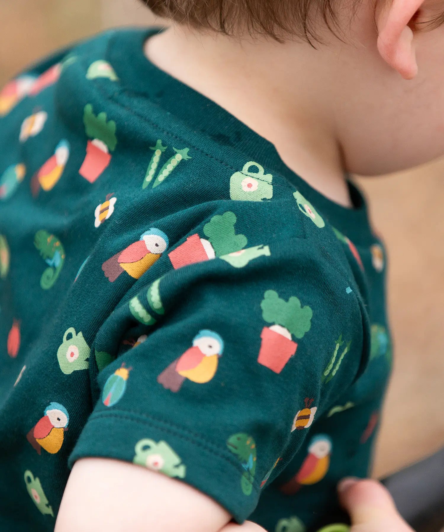 Close up of the repeat garden illustration themed print on the t-shirt from the Little Green Radicals Spring garden organic cotton playset being worn. 
