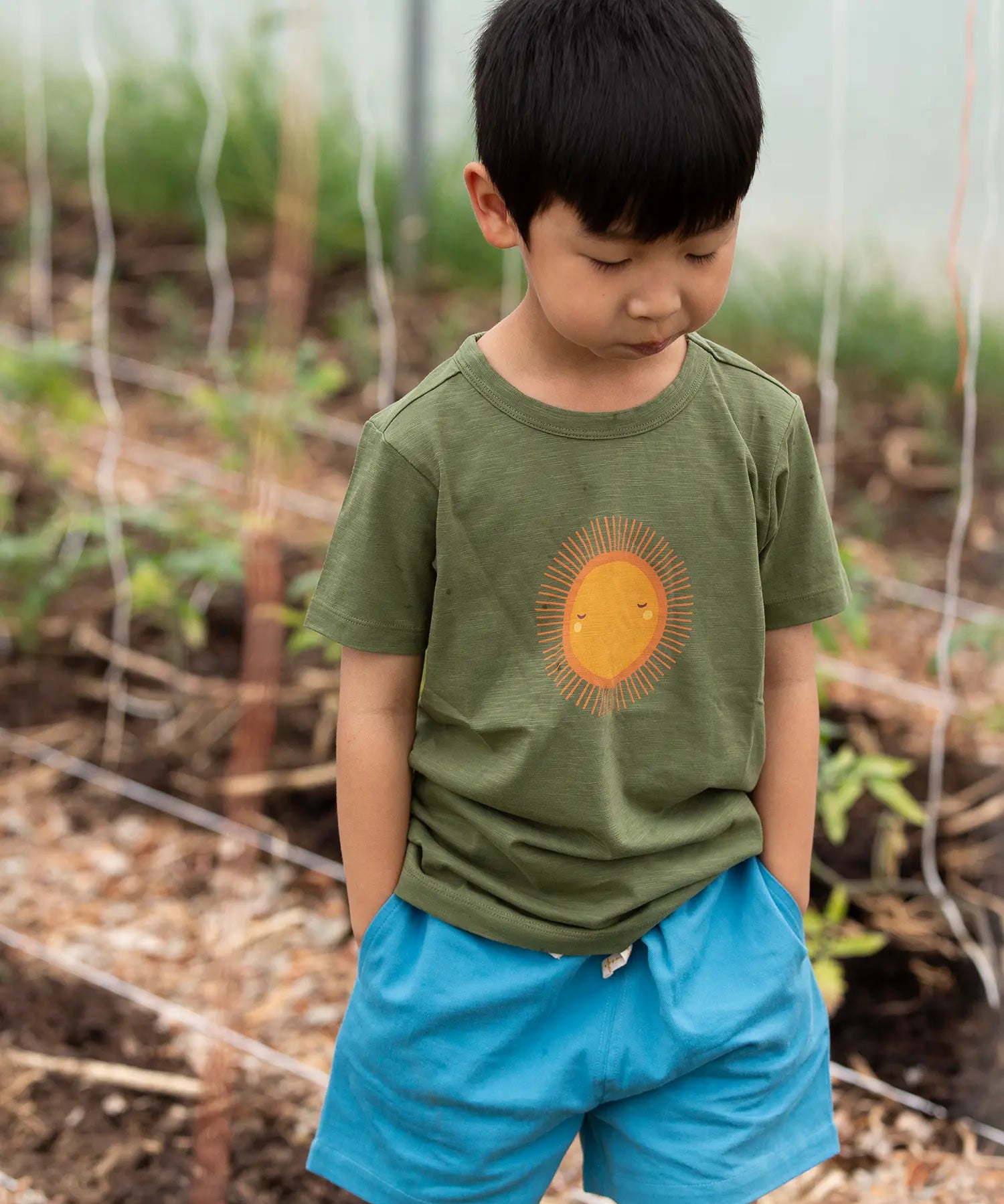Child wearing the Little Green Radicals Summer rays sunshine short sleeve green organic-cotton t-shirt with blue shorts