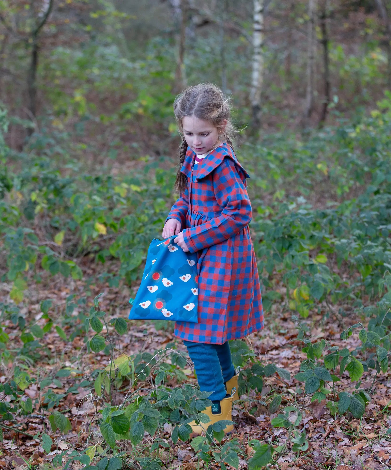 Child holding a Little Green Radicals  sun birds print blue recycled waterproof wet bag.