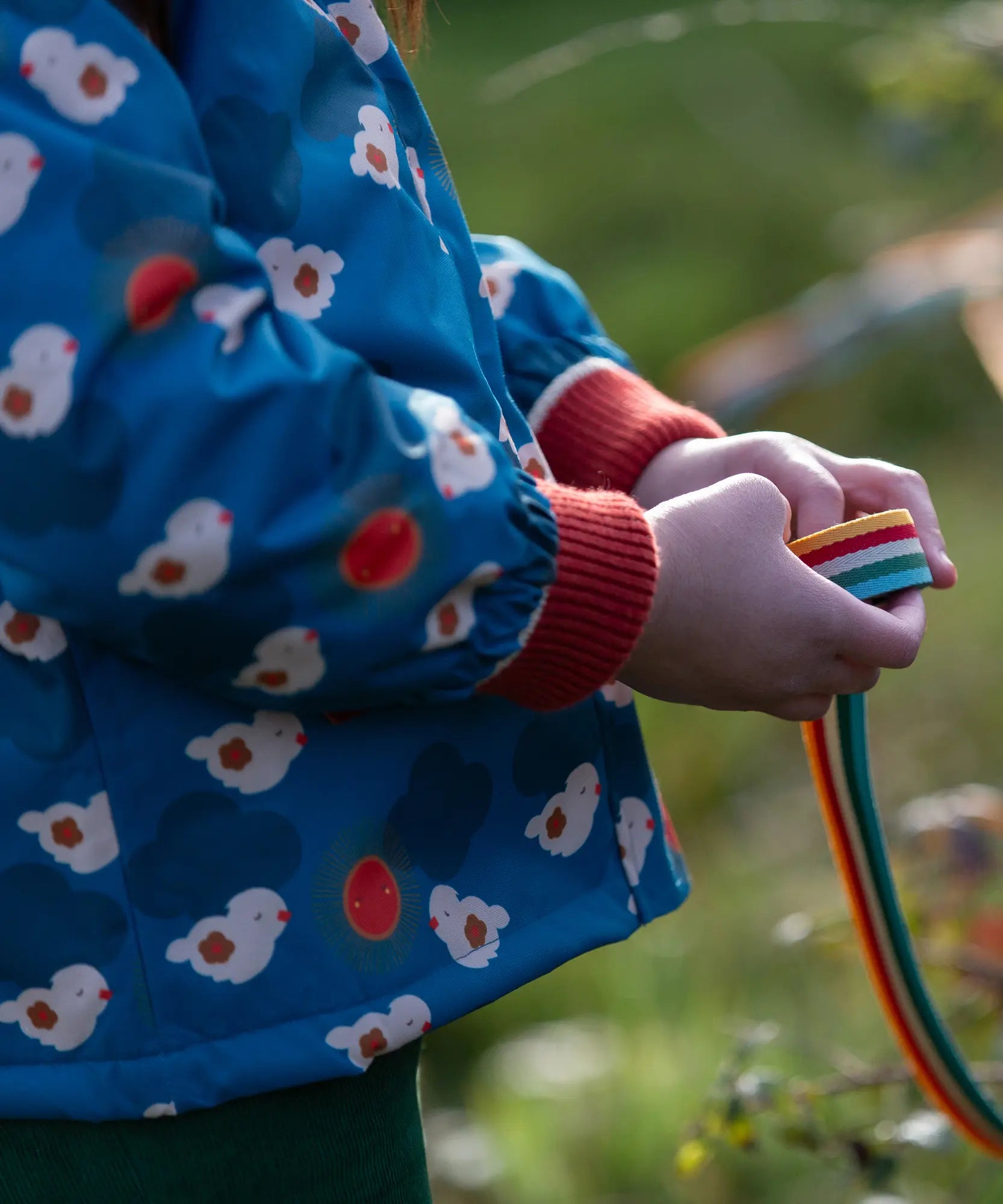 Close up of a child wearing a Little Green Radicals blue sun birds recycled waterproof adventure Winter coat.