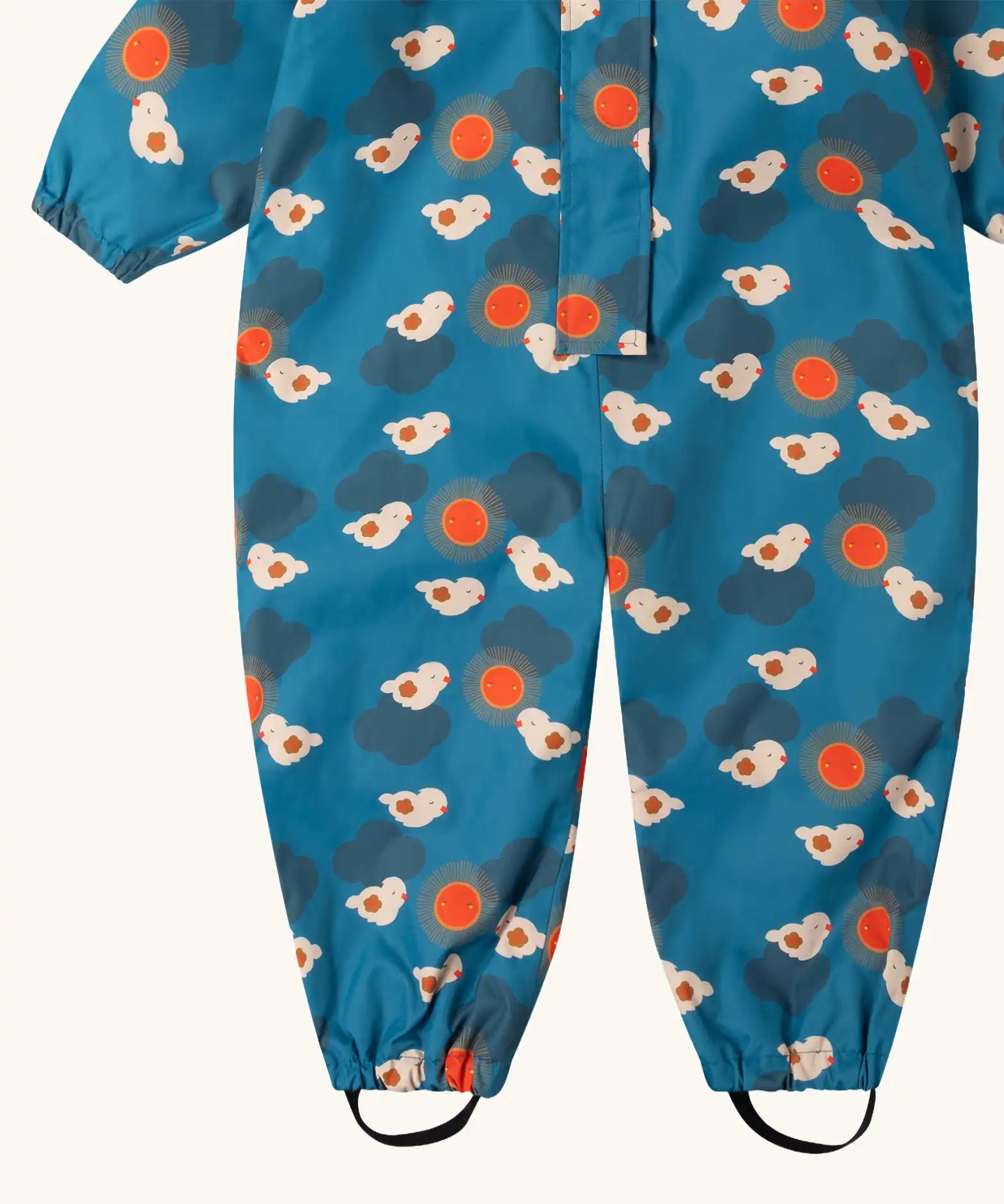 Close up of the foot straps on the Little Green Radicals sun birds recycled waterproof winter all in one suit. Blue background with white birds and orange sun. 