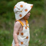 Child wearing the Little Green Radicals summer sun reversible cream sunhat on the repeat sun print side. 