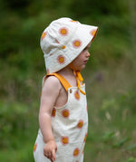 Child wearing the Little Green Radicals summer sun reversible cream sunhat on the repeat sun print side. 