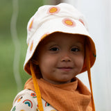 Child wearing the Little Green Radicals summer sun reversible cream sunhat on the repeat sun print side. 