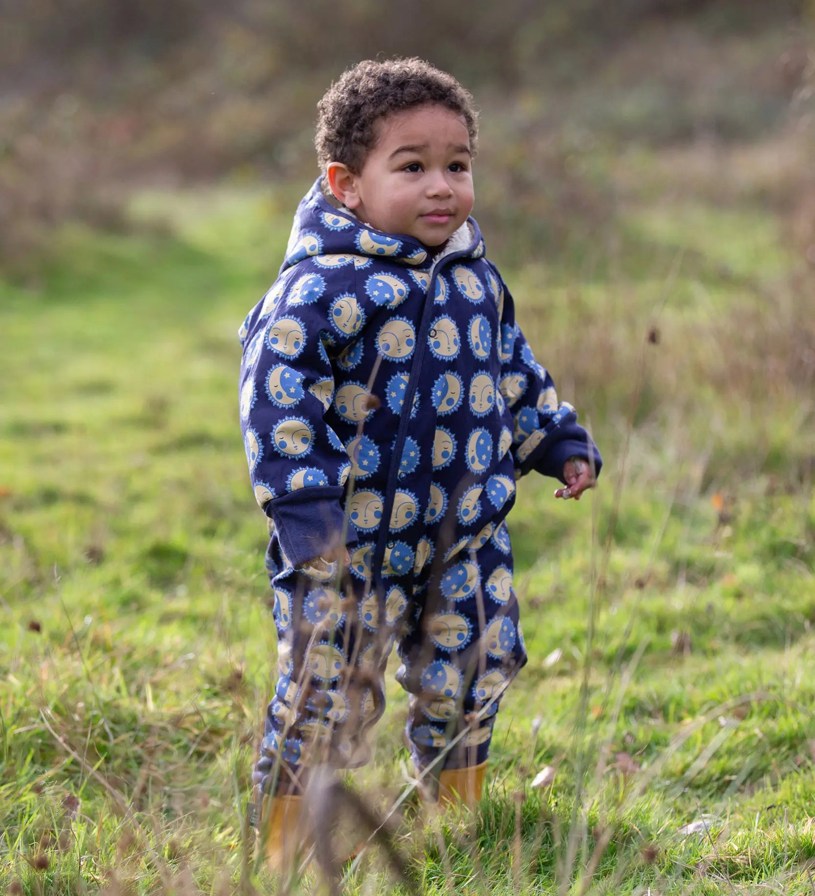 Young child wearing a Little Green Radicals sun folk blue sherpa fleece lined snowsuit.