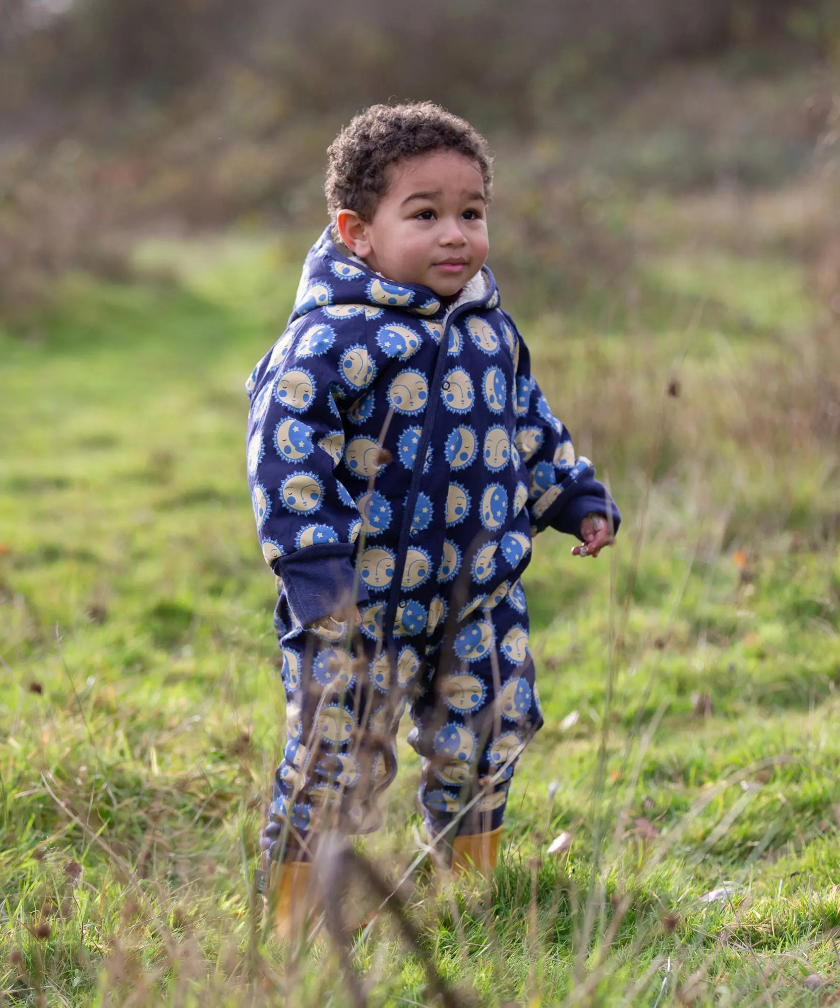 Young child wearing a Little Green Radicals sun folk blue sherpa fleece lined snowsuit.
