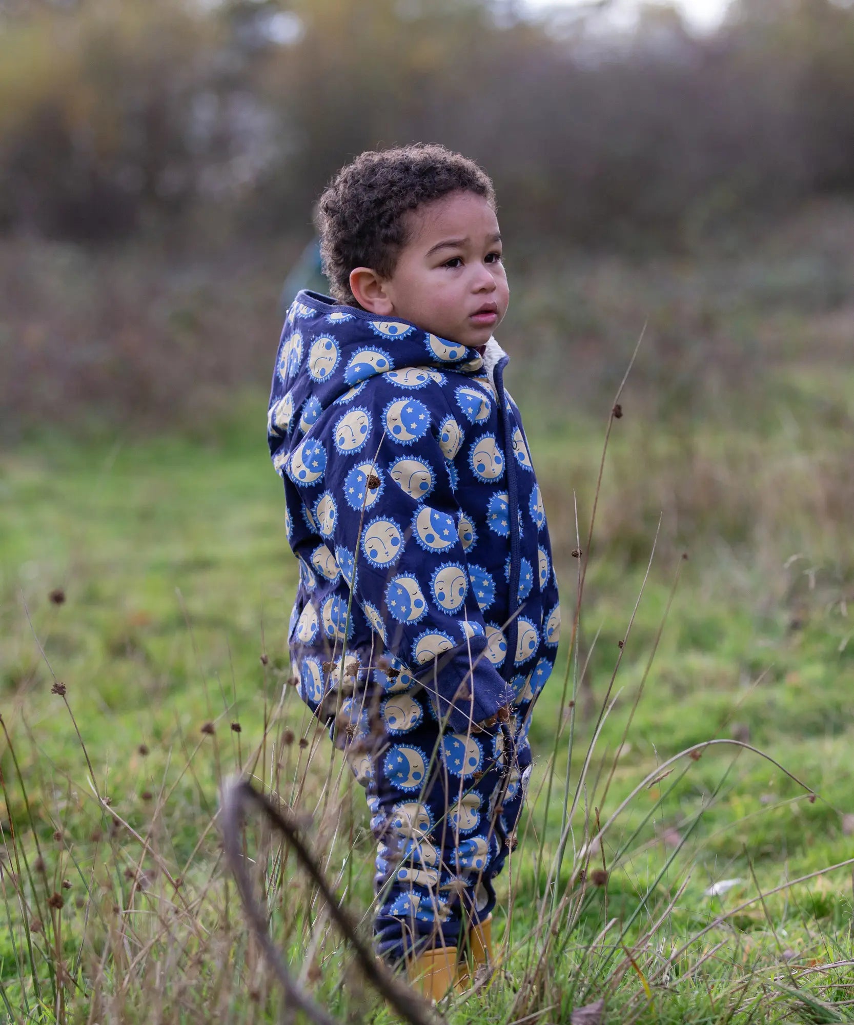 Young child wearing a Little Green Radicals sun folk blue sherpa fleece lined snowsuit.