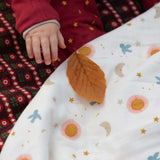 A close up of a babies hand reaching for a leaf that has been placed on the Little Green Radicals moin and sun print Organic Sherpa Hooded Baby Blanket in front of them. This blanket  is a part of a wide range of organic cotton clothing and accessories for children available here at Babipur. 
