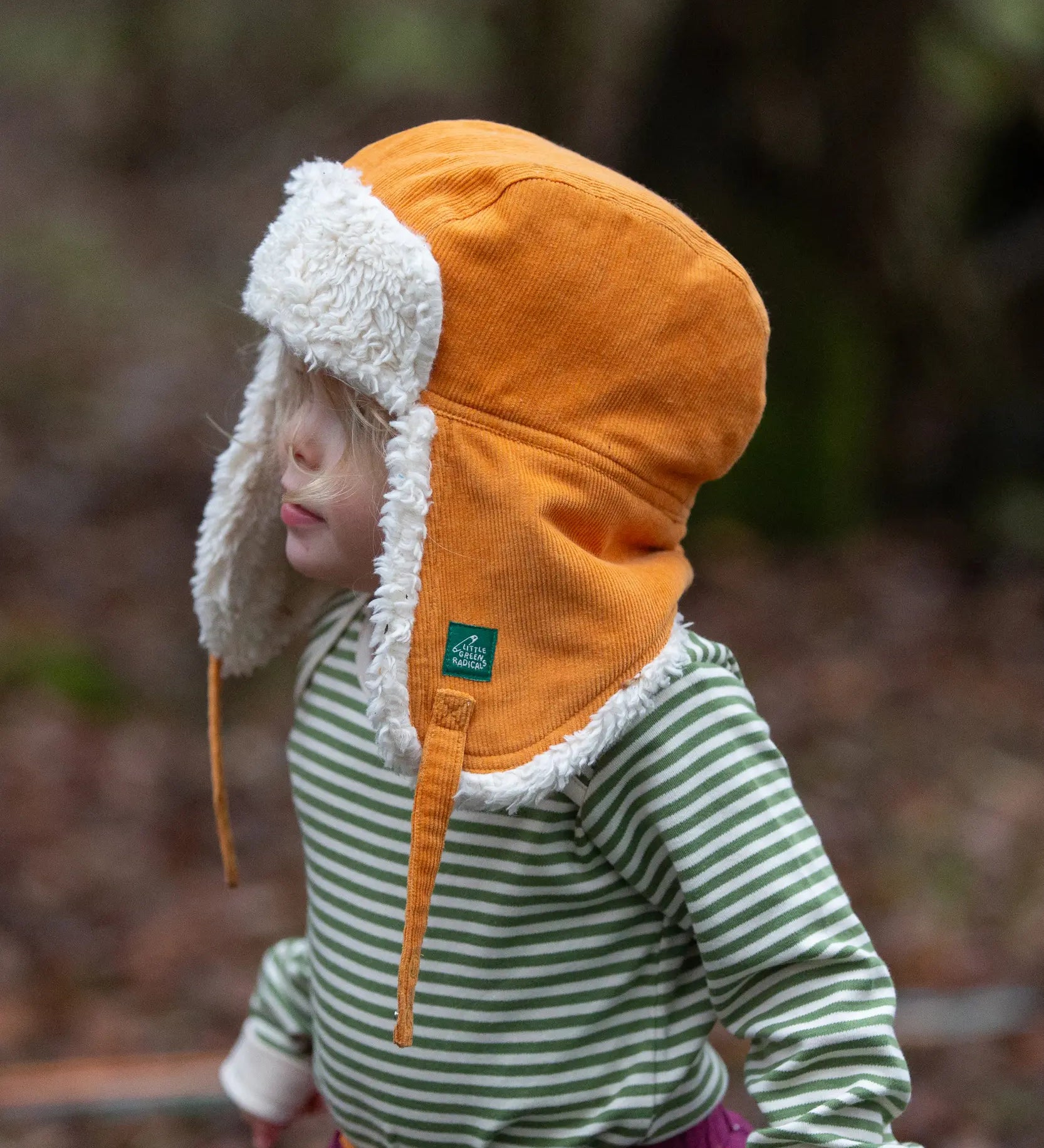 Baby wearing the Little Green Radicals sherpa fleece lined yellow gold corduroy cosy hat.