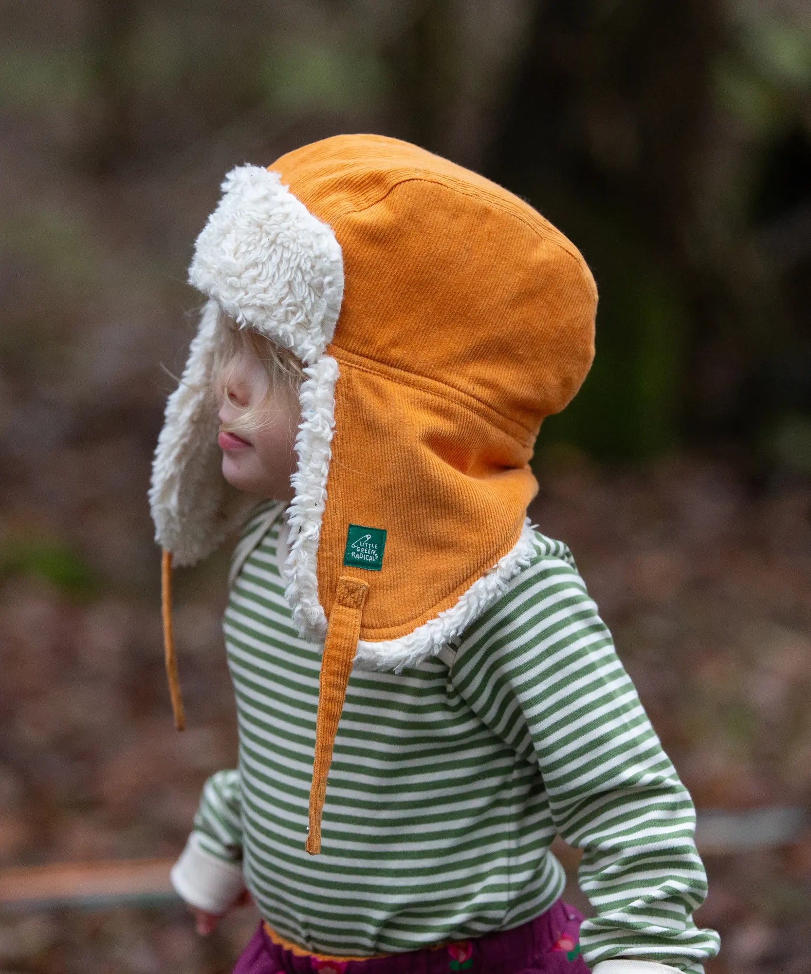 Baby wearing the Little Green Radicals sherpa fleece lined yellow gold corduroy cosy hat.
