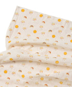 A close up of the rainbow and sunshine print on the muslin from the Little Green Radicals Sunshine & Rainbows Organic Baby Muslin Set. A  2 Pack of muslin cloths, one is plain yellow gold and the other has an all over print featuring rainbows, sun and rainbow rain clouds. Little green Radicals have a wide range of organic cotton, Fairtrade children's clothing and outerwear available here at Babipur.