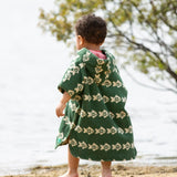 Little Green Radicals swimming fish organic cotton hooded towel poncho on child, view of back. Cream fish pattern on a green background.