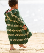 Back of a child wearing the Little Green Radicals swimming fish organic cotton hooded towel poncho, the hood has a pink coloured hood lining. Cream fish pattern on a green background.