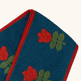 Close up of the Little Green Radicals tulips knitted blue scarf. Blue scarf with red tulips and red trim.