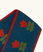 Close up of the Little Green Radicals tulips knitted blue scarf. Blue scarf with red tulips and red trim.