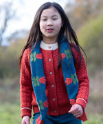 Child wearing Little Green Radicals tulips knitted blue scarf. Blue scarf with red tulips.