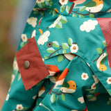 Close up of the popper closure on the hood of the Little Green Radicals turquoise birds recycled waterproof kids raincoat. Repeat pattern featuring bird on blossom branches.