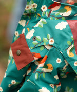 Close up of the popper closure on the hood of the Little Green Radicals turquoise birds recycled waterproof kids raincoat. Repeat pattern featuring bird on blossom branches.