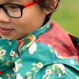 Close up of the mesh lining on the hood of the Little Green Radicals turquoise birds recycled waterproof kids raincoat. Repeat pattern featuring bird on blossom branches.