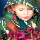 Close up of a child wearing the Little Green Radicals feast waterproof recycled kids raincoat with the hood up.