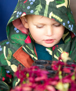 Close up of a child wearing the Little Green Radicals feast waterproof recycled kids raincoat with the hood up.