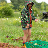 Child wearing the Little Green Radicals feast waterproof recycled kids raincoat with blue pinstripe shorts underneath with yellow wellington boots. 
