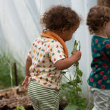 Close up of the repeat pattern print featuring nature themed illustrations top from the Little Green Radicals vintage style rainbows organic cotton t-shirt & jogger playset being worn. 