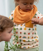 Close up of the repeat pattern print featuring nature themed illustrations top from the Little Green Radicals vintage style rainbows organic cotton t-shirt & jogger playset being worn by a toddler. 