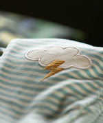 Close up of the applique cloud with bolt of yellow thunder on the Little Green Radicals weather knee patch blue and cream striped organic cotton joggers.
