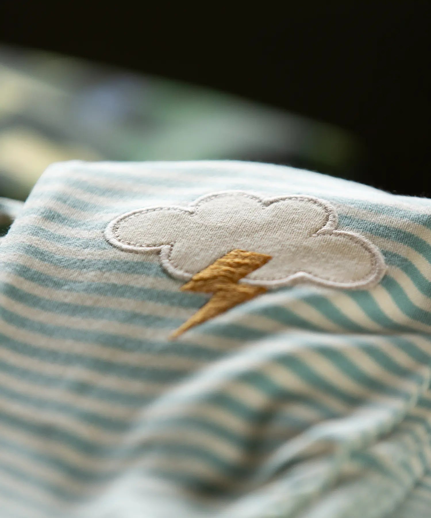 Close up of the applique cloud with bolt of yellow thunder on the Little Green Radicals weather knee patch blue and cream striped organic cotton joggers.