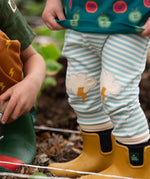 Close up of Little Green Radicals weather knee patch blue and cream striped organic cotton joggers being worn with yellow wellington boots. 