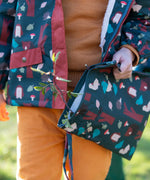 Child holding a Little Green Radicals  woodeland print green recycled waterproof wet bag wearing a coat and gloves in the same print.