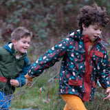 Child wearing a Little Green Radicals woodland world green recycled waterproof adventure winter coat with yellow gold trousers.