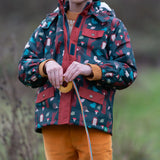 Child wearing a Little Green Radicals woodland world green recycled waterproof adventure winter coat with yellow gold trousers.