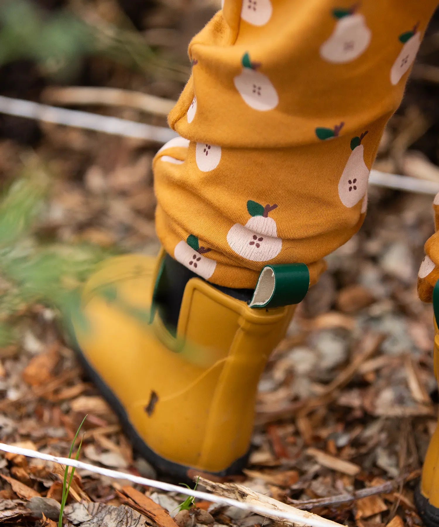 Close up of the bottoms of the Little Green Radicals yellow gold comfy organic cotton kids joggers being worn with yellow wellington boots.