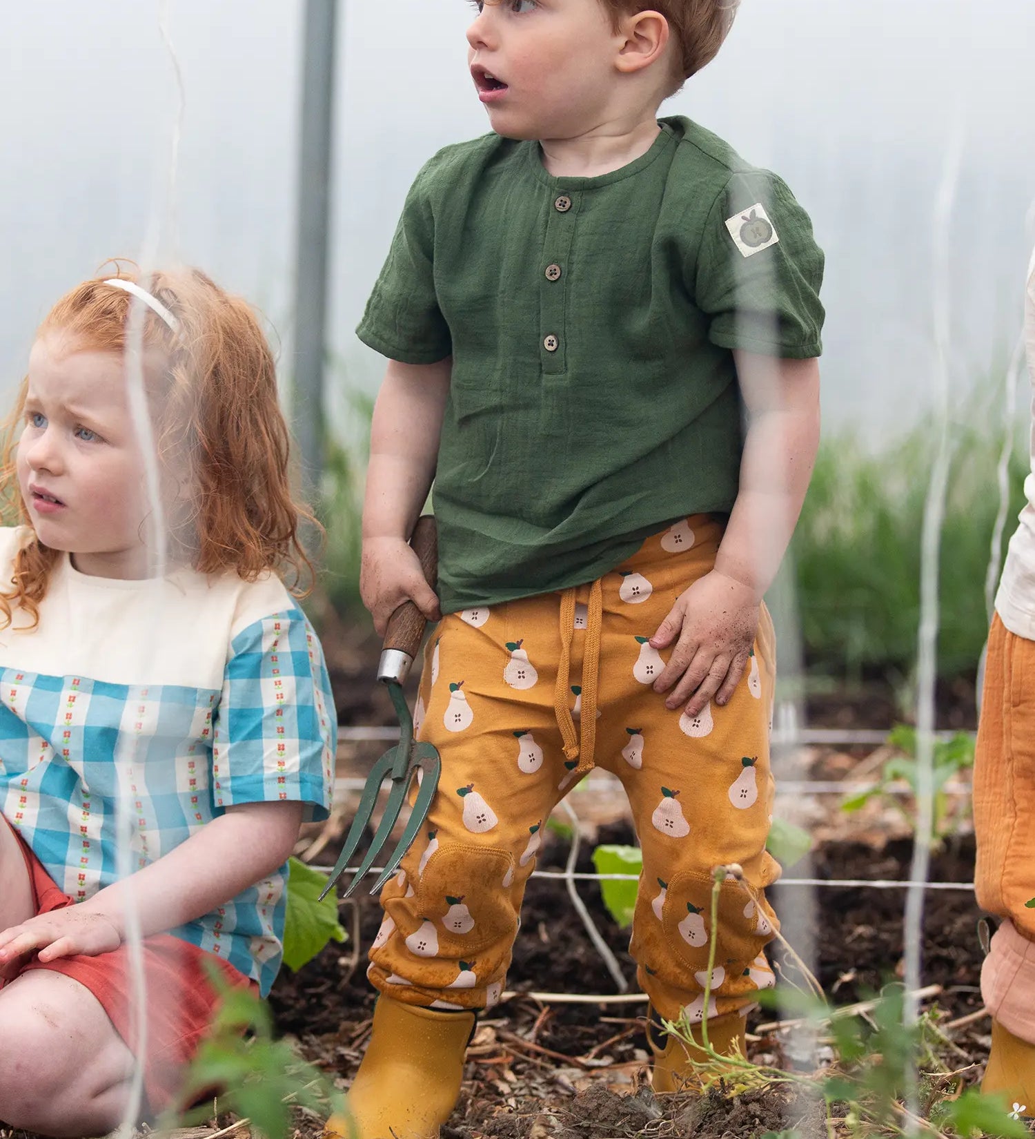 Child wearing the Little Green Radicals yellow gold comfy organic cotton kids joggers with a green muslin henley t-shirt and yellow wellington boots.