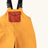 Close up of the rust orange pocket on the Little Green Radicals yellow gold recycled lined waterproof dungarees.