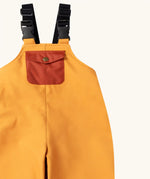 Close up of the rust orange pocket on the Little Green Radicals yellow gold recycled lined waterproof dungarees.