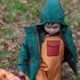 Child wearing the Little Green Radicals yellow gold recycled lined waterproof dungarees with a green coat.  