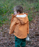 Back of a child wearing a Little Green Radicals yellow gold recycled waterproof 3 in 1 coat with green waterproof dungarees underneath.