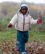 Child wearing the fleece jacket layer from the Little Green Radicals  yellow gold recycled waterproof 3 in 1 coat with blue corduroy trousers.