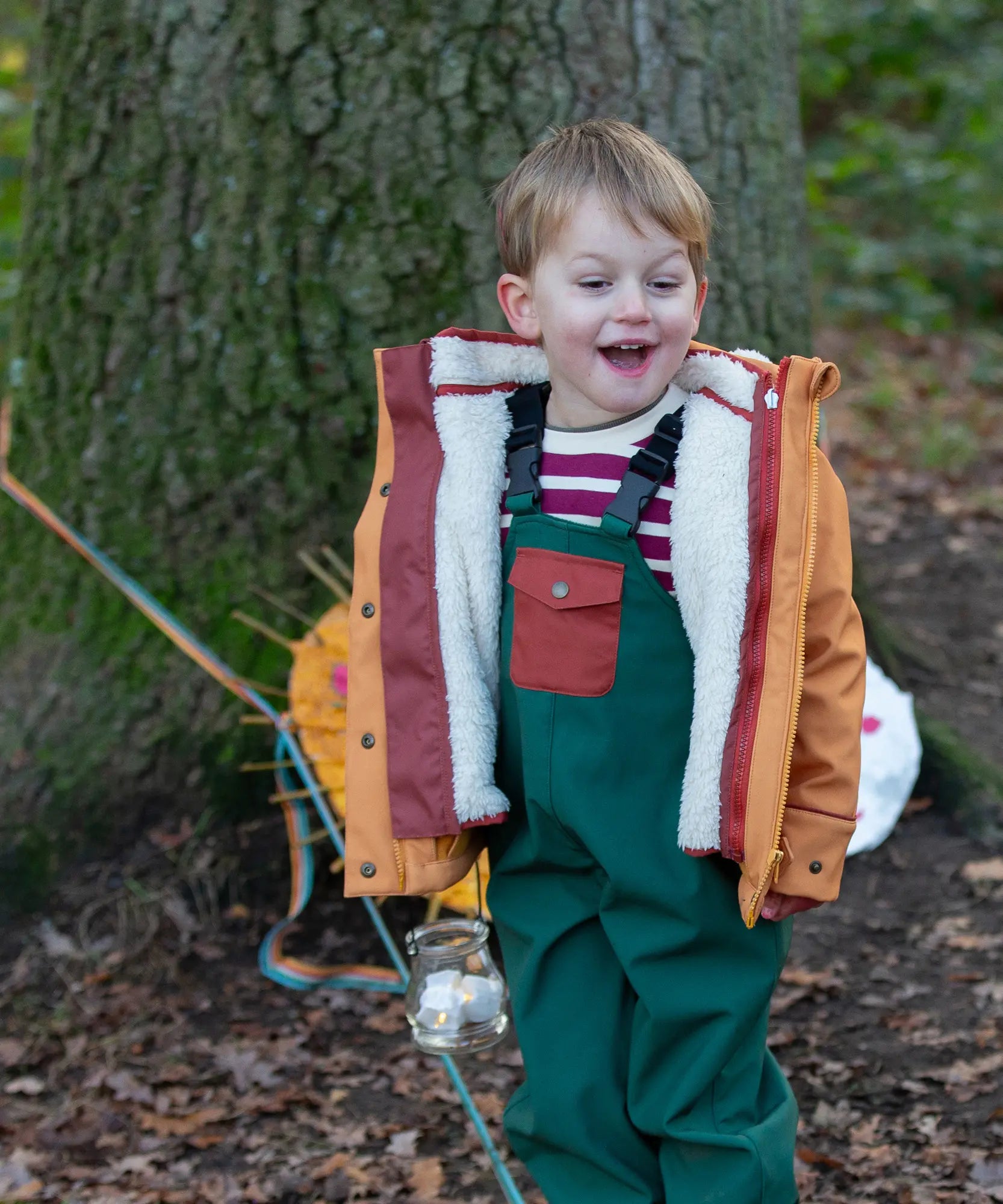 Child wearing a Little Green Radicals  yellow gold recycled waterproof 3 in 1 coat with green waterproof dungarees.