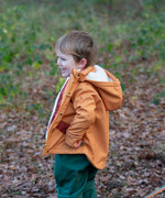 Side of a child wearing a Little Green Radicals yellow gold recycled waterproof 3 in 1 coat with green waterproof dungarees underneath.