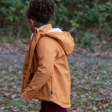 Child wearing a Little Green Radicals  yellow gold recycled waterproof 3 in 1 coat with berry purple trousers. Side view.