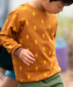 Close up of child wearing the Little Green Radicals kids yellow lightning print organic cotton sweatshirt.